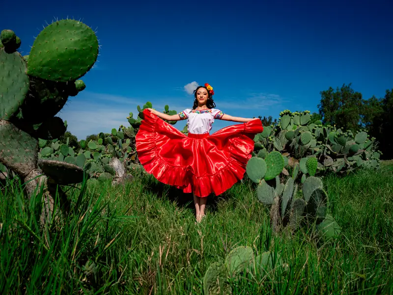 Mujer con vestimenta de folclor mexicano bailando entre nopales