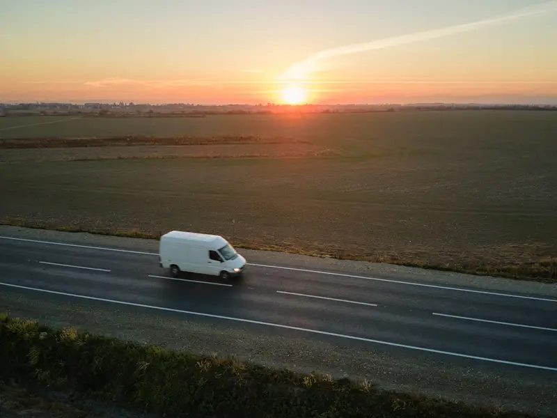 Camioneta de reparto recorriendo una carretera rural al atardecer